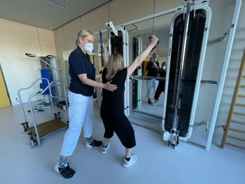 Bild Patientin und Physiotherapeutin bei einer Übung an einem Fitnessgerät
