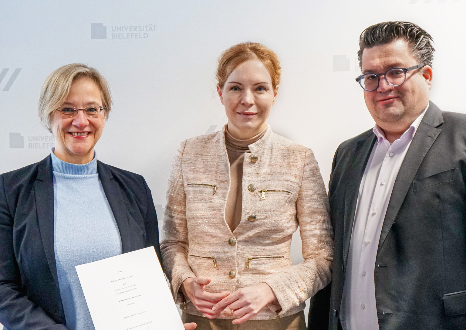 Die Rektorin der Universität Bielefeld Prof. Dr. Angelika Epple (l.) übergibt Univ.-Prof. Dr. Selma Ugurel (Mitte) ihre Ernennungsurkunde im Beisein von Bernd Henkemeier, Kaufmännischer Direktor des Klinikum Bielefeld (r.).