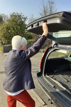 Bild Oberarmkopffraktur Patientin öffnetn den Kofferraum ihres Autos